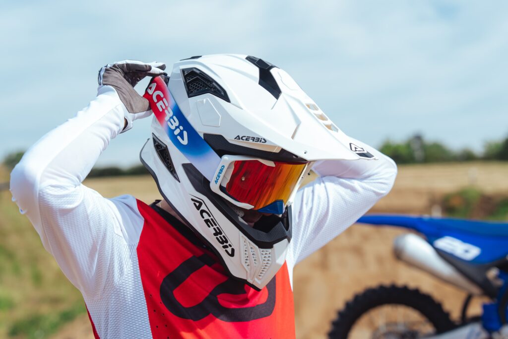 Pilote enduro enfilant un masque Acerbis Vortex lentille miroir sur casque tout-terrain