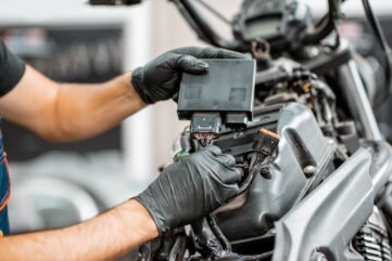 Mécanicien ganté qui branche le calculateur électronique (ECU) d’une moto en atelier