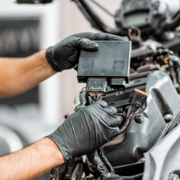 Mécanicien ganté qui branche le calculateur électronique (ECU) d’une moto en atelier