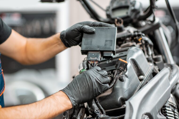 Mécanicien ganté qui branche le calculateur électronique (ECU) d’une moto en atelier