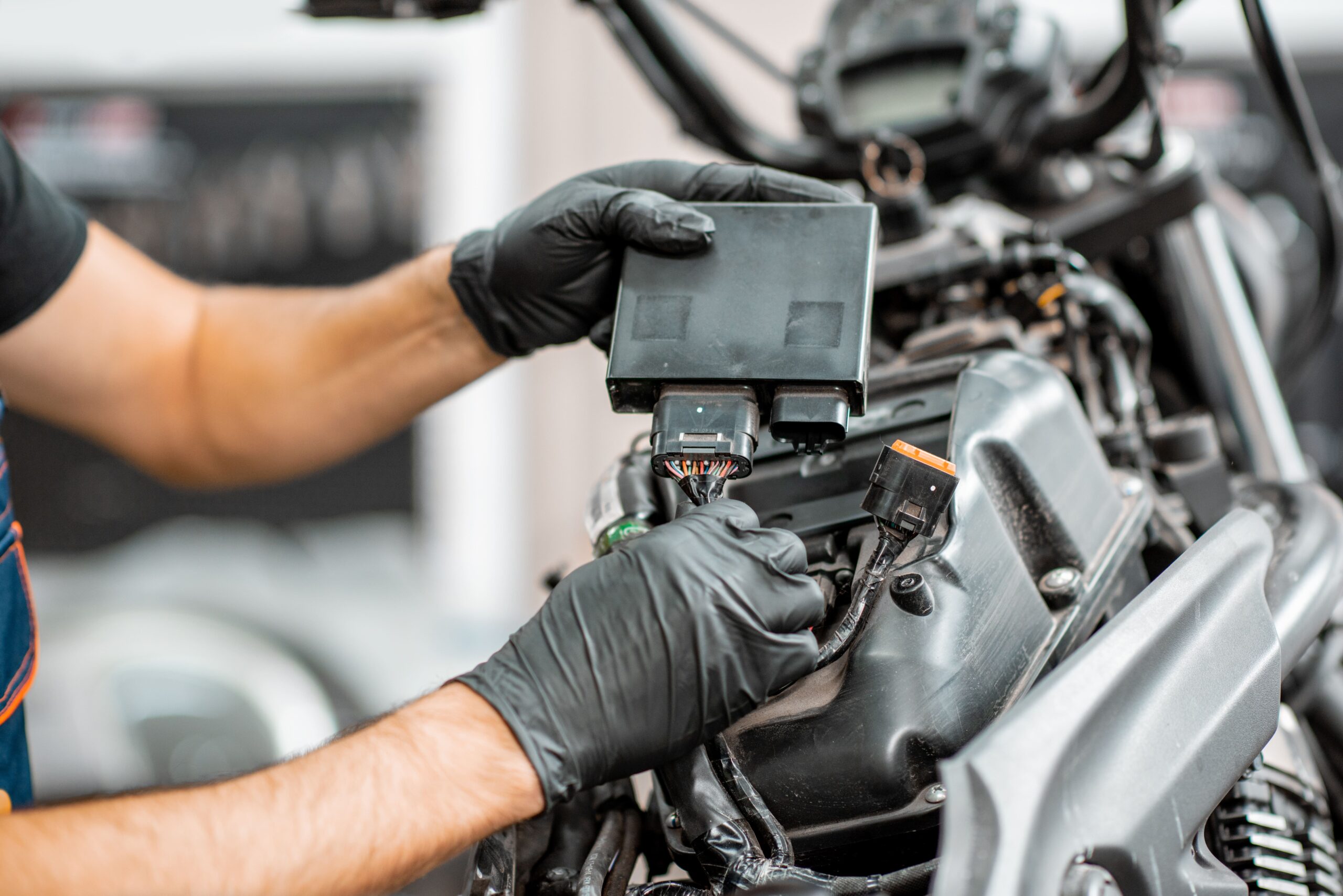 Mécanicien ganté qui branche le calculateur électronique (ECU) d’une moto en atelier